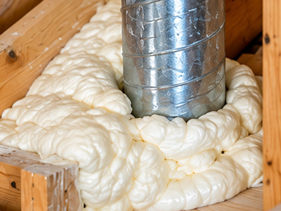 Close-up of spray foam insulation installed around an attic duct penetration