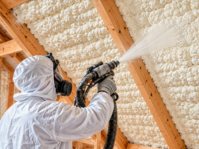 Technician professionally applying spray foam insulation inside an attic